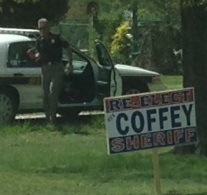 Charles County Md. Sheriff Rex Coffey on his way to secure a sign while in uniform and driving a county police car.