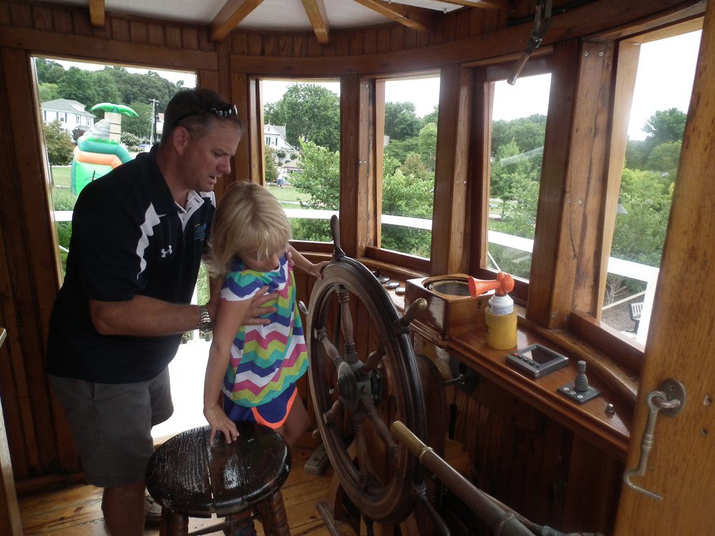 The present owner and master of the Iva W., Scott, hosts a family  for a tour of the pilot house and even the engine room of the ship. The Iva W has had three engines in its lifetime, with the Caterpillar 13000 diesel engine which was installed about the end of WWII. THE CHESAPEAKE TODAY photo