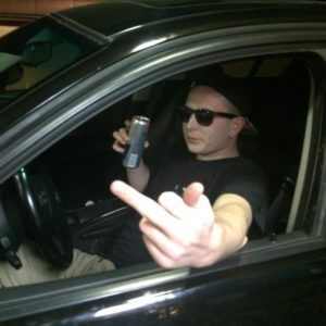 JAMES-C.-PAVLIKOWSKI-with-beer-in-car-and-finger. Pavlikowski posted numerous photos of himself in similar poses and lamented not having a car to drive. 